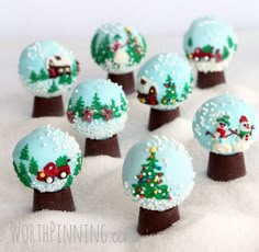 there are many christmas decorations on top of the snow covered trees and balls in the shape of houses