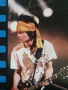 a man with a bandanna on his head playing an electric guitar at a concert