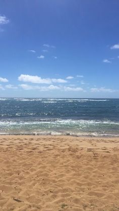 a person is walking on the beach with a surfboard in their hand and some water behind them