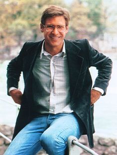 a man sitting on top of a metal hand rail next to a river and trees