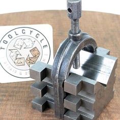 a piece of metal sitting on top of a wooden table next to a small business card