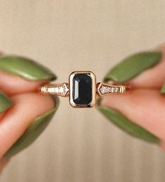 a woman's hand holding a black and white stone ring with diamonds on it