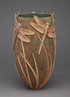 a ceramic vase with dragonflies on it