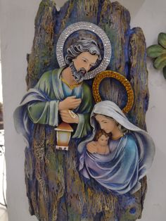 an image of the virgin mary and child jesus on a tree stump with foliage around it