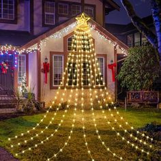 a christmas tree is lit up in front of a house with lights on the roof