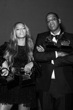 two people standing next to each other holding trophies