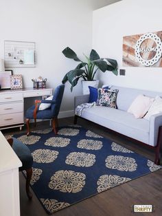 a living room filled with furniture and a blue rug on top of a hard wood floor