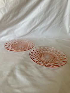 two red glass plates sitting on top of a white sheet