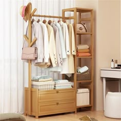 an organized closet with clothes and handbags hanging on the rack, in front of a window