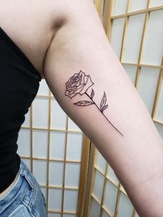 a woman's arm with a rose tattoo on the left side of her arm