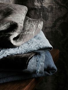 three folded blankets sitting on top of a wooden table