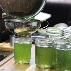 green liquid is being poured into mason jars