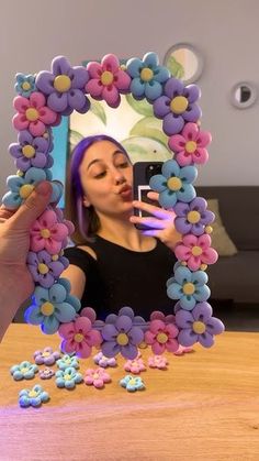 a woman taking a selfie in front of a mirror with flowers on the frame