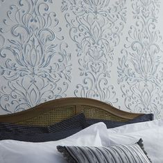 a bed with white sheets and pillows in front of a wallpapered headboard