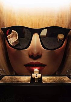 a woman's face is reflected in the mirror while wearing sunglasses and holding a ring