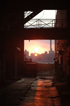 the sun is setting over an alley way