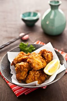 a bowl filled with fried food next to a lemon wedge