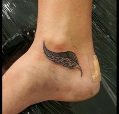 a tattoo on the foot of a person with a feather in it's tail