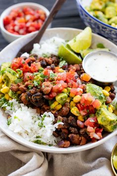 a bowl filled with rice, beans and avocado next to two bowls of salsa