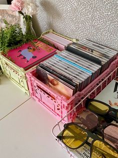 a bunch of cds sitting on top of a table next to sunglasses and a book