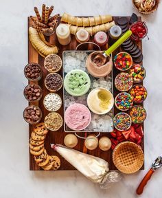 an assortment of desserts and pastries are arranged on a wooden tray with ice cream