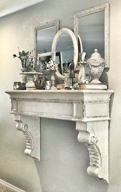 a white mantle with mirrors and vases on it