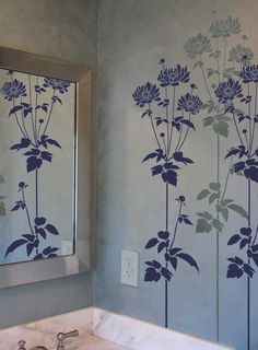 a bathroom wall with flowers painted on it and a mirror in front of the sink