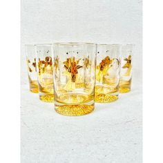 four glasses with gold designs on them are lined up