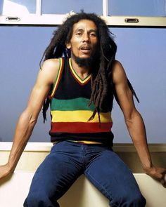 a man with dreadlocks is sitting on a toilet and posing for the camera