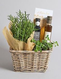 a wicker basket filled with herbs and bottles of olive oil next to a card