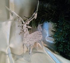 a glass reindeer ornament sitting on top of a white cloth covered tablecloth