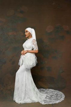 a woman in a white dress and veil posing for the camera with her hands on her hips