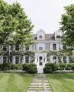 a large house with white shutters and trees