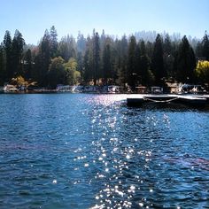 the sun shines on the water and boats are docked in the lake near some trees