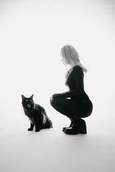 a woman kneeling down next to a cat