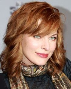 a woman with red hair wearing a scarf and black shirt is looking at the camera