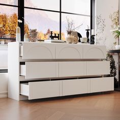 a kitchen with white cabinets and wooden floors next to a large window overlooking the mountains