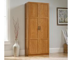 a tall wooden cabinet sitting next to a window in a room with hardwood flooring