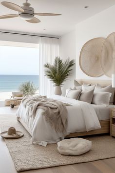 a bedroom with a large bed next to a window overlooking the ocean and palm trees