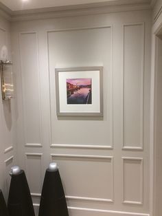 two black lamps sitting next to each other in front of a painting on the wall