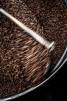 coffee beans are being stirred in a bucket