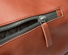 an open zipper on a brown leather bag