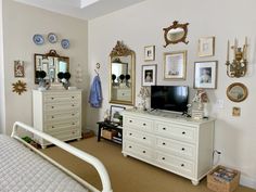 a bedroom with white furniture and lots of pictures on the wall above the dressers