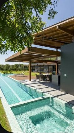 an outdoor hot tub next to a swimming pool in the middle of a lush green field