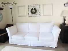 a living room with white furniture and pictures on the wall