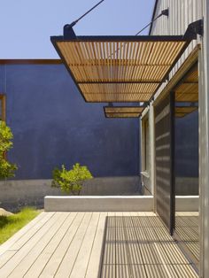 an outdoor covered patio area with wooden flooring and pergolated roof over it