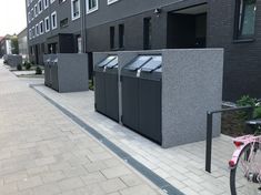 a row of black trash cans sitting next to a pink bike