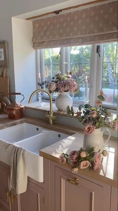 a kitchen sink with flowers on the counter top and windows in the backround