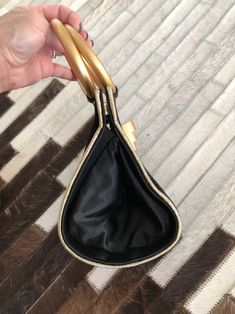 "When vintage looks this modern, it's a great thing. This black and gold evening bag/tiny tote is tres chic. So good with just about anything. Small but interestingly, roomy enough to hold a whole bunch cos of the wide roundish base. Measures 5-1/4\" (width) x 6\" (height excluding handles) x 5\" (base width) Condition: Excellent. Minor wear on gold rings. This bag is clean and ready to use. Comes from a smoke and pet free home. Don't forget to follow me on Instagram @tammaraclearshercloset for Chic Gold Shoulder Bag With Handles, Gold Top Handle Evening Bag, Elegant Evening Bags With Brass Hardware, Gold Satchel Evening Bag With Top Carry Handle, Gold Evening Bag With Double Handle And Gold-tone Hardware, Gold Handheld Evening Bag For Shopping, Retro Gold Bags With Gold-tone Hardware, Gold Retro Bags With Gold-tone Hardware, Gold Shoulder Bag With Double Handle For Party