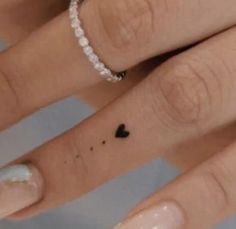 two fingers with small hearts on them, one has a diamond band and the other has a black heart